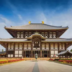 Majestatyczna japońska świątynia Todai-ji w Nara, z imponującym dachem i drewnianą konstrukcją, pod błękitnym niebem.