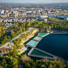 Widok na jezioro Zakrzówek z basenami i drewnianymi pomostami, otoczone zielenią i zabudową miejską.
