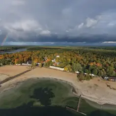Jesioro Niedzięgiel jesienią, z tęczą na niebie i piaszczystą plażą.