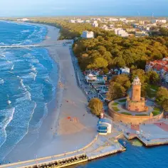 Widok na port w Kołobrzegu z latarnią morską, plażą i morzem.