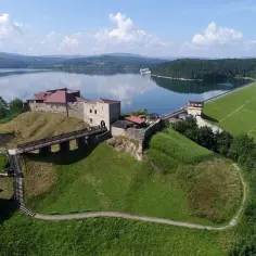Zamek na wzgórzu nad jeziorem Dobczyckim. Atrakcje turystyczne obejmują zamek, zaporę i malownicze widoki.