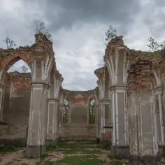 Ruiny kościoła na Podlasiu, zarośnięte trawą, z widokiem na pochmurne niebo. Nietypowe atrakcje Podlasia, które budzą wyobraźnię.
