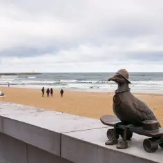 Pomnik mewy na deskorolce na plaży, idealne miejsce, gdzie na wakacje. W tle morze i spacerowicze.