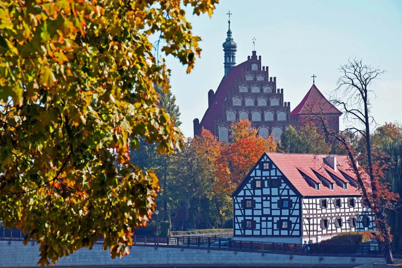 Jesienne bydgoszcz atrakcje na weekend: malowniczy dom szachulcowy i zabytkowe kościoły na tle kolorowych drzew.
