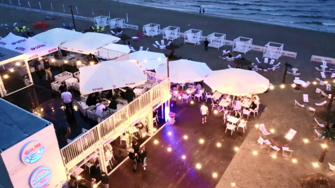 Wieczorny relaks na plaży w Trójmieście. Stoliki, leżaki i białe namioty tworzą klimat idealny na trójmiasto atrakcje dla dorosłych.