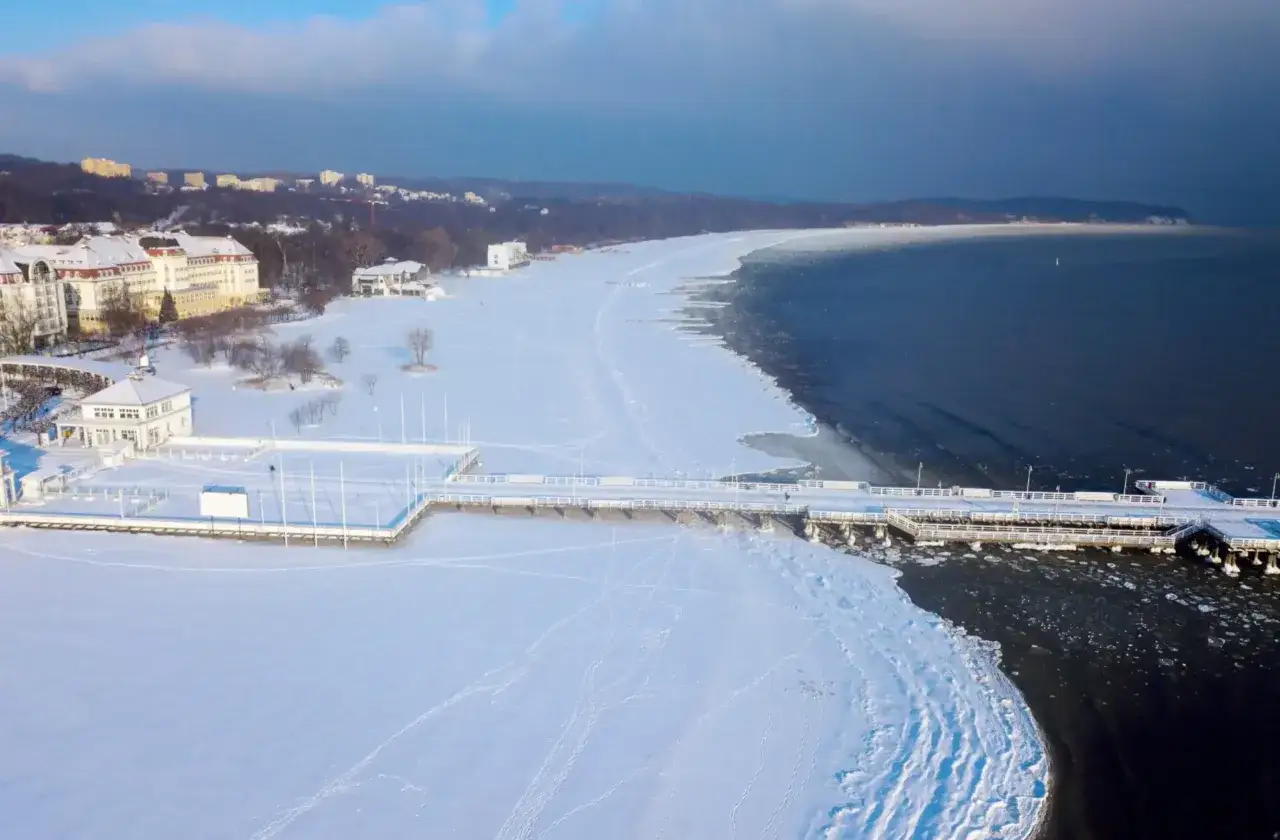 Zimowy Sopot z molo i plażą pokrytą śniegiem. Idealne miejsce, gdzie na ferie zimowe, by podziwiać mroźne piękno Bałtyku.