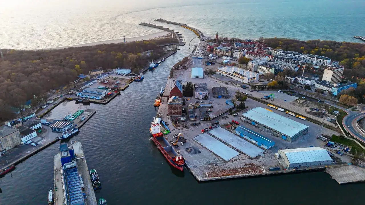 Kołobrzeg plan miasta dworzec PKP: widok z lotu ptaka na port, kanał, statki, budynki i plażę.