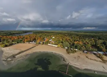 Jesioro Niedzięgiel jesienią, z tęczą na niebie i piaszczystą plażą.