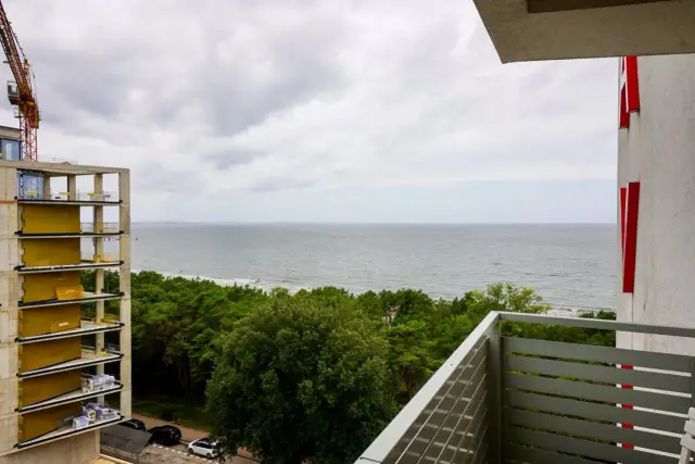 Widok na morze z budowy hotelu Slavia Międzyzdroje. Widać fragment budowanego obiektu, las i plażę.
