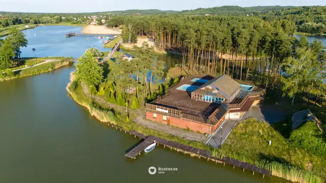 Krasnobród zalew z lotu ptaka: kompleks basenów, drewniany budynek, plaża i las.