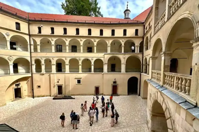 Dziedziniec zamku w Ojcowski Park Narodowy z arkadowymi krużgankami i grupą turystów.